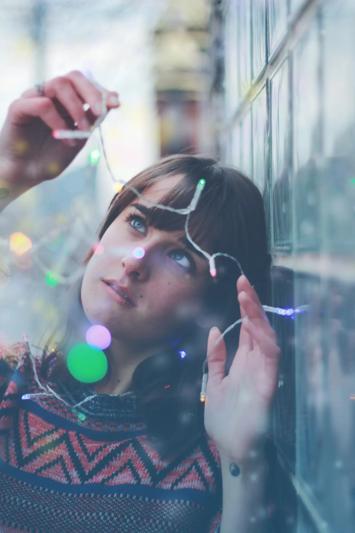 woman holding holiday lights looking at them in wonder